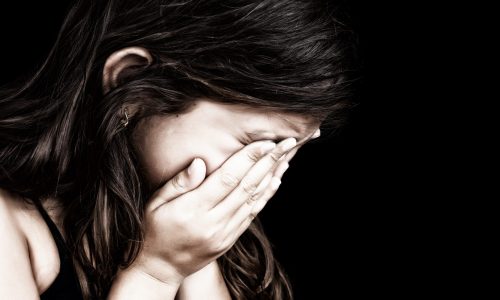 Photo of a young girl with her head in her hands.