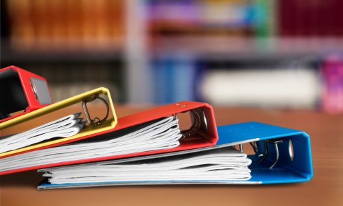 3 ring binders in yellow, red and blue sitting on a table.