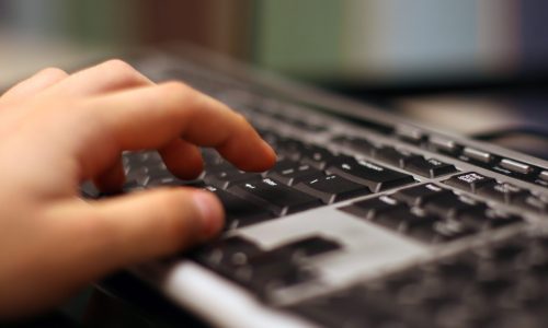 A hand typing on a keyboard.