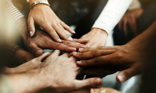 Photo of people standing in a circle and putting their hands together