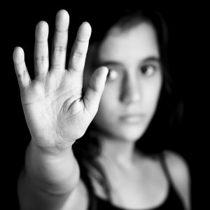 Greyscale photo of young woman putting her hand up in a stop motion.