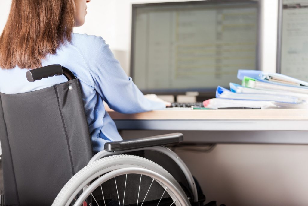 Photo of a woman in a wheelchair working at a computer desk