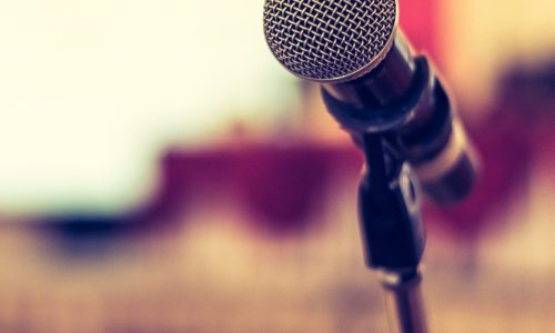 Photo of microphone with a seminar room in the background.