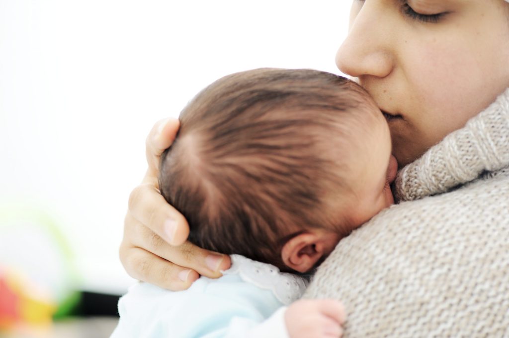 Photo of a woman holding her baby close.