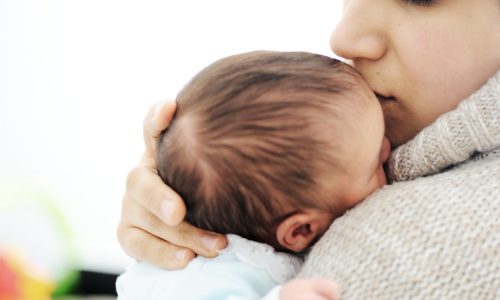 Photo of a woman holding her baby close.