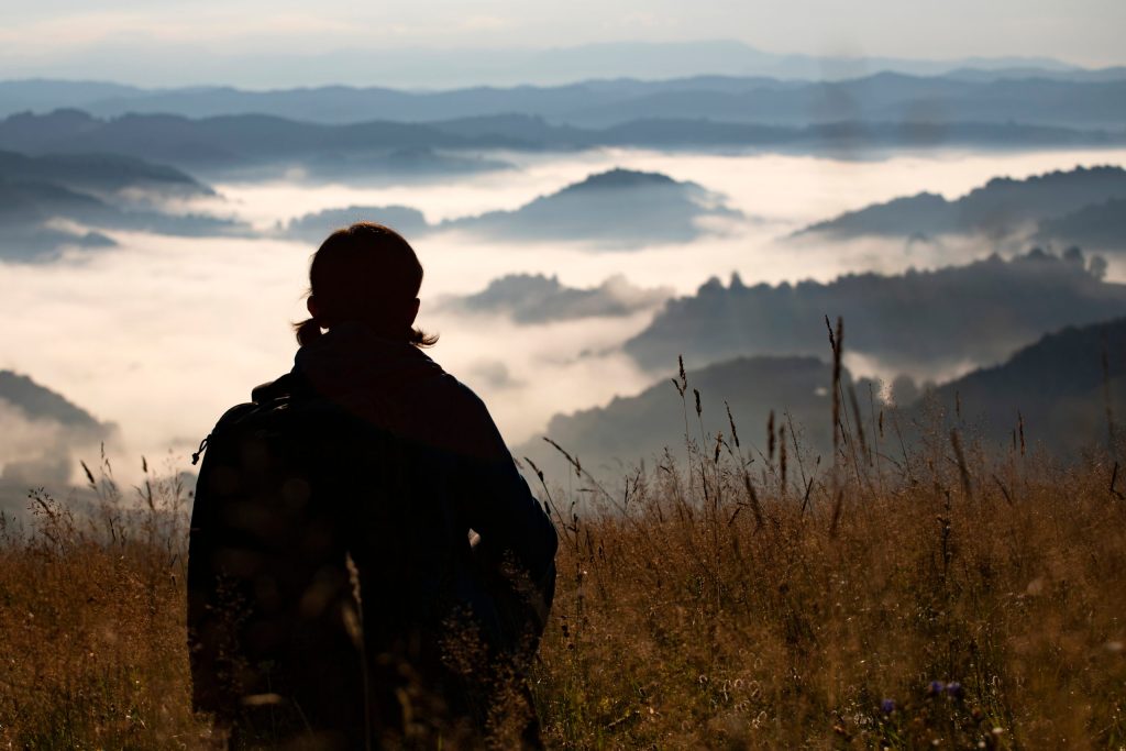 the outline of a woman looking out over mountains