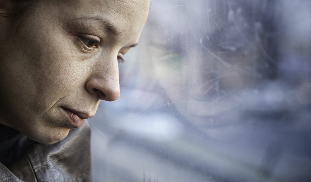 A photo of a woman looking down out of a window.