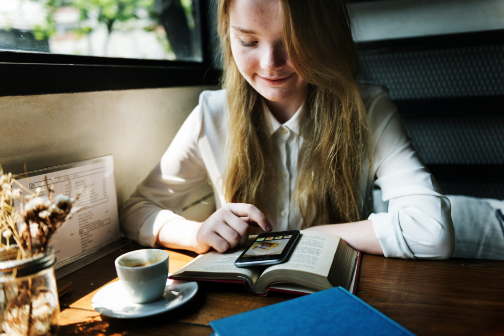 A photo of a young woman using her phone at a cafe