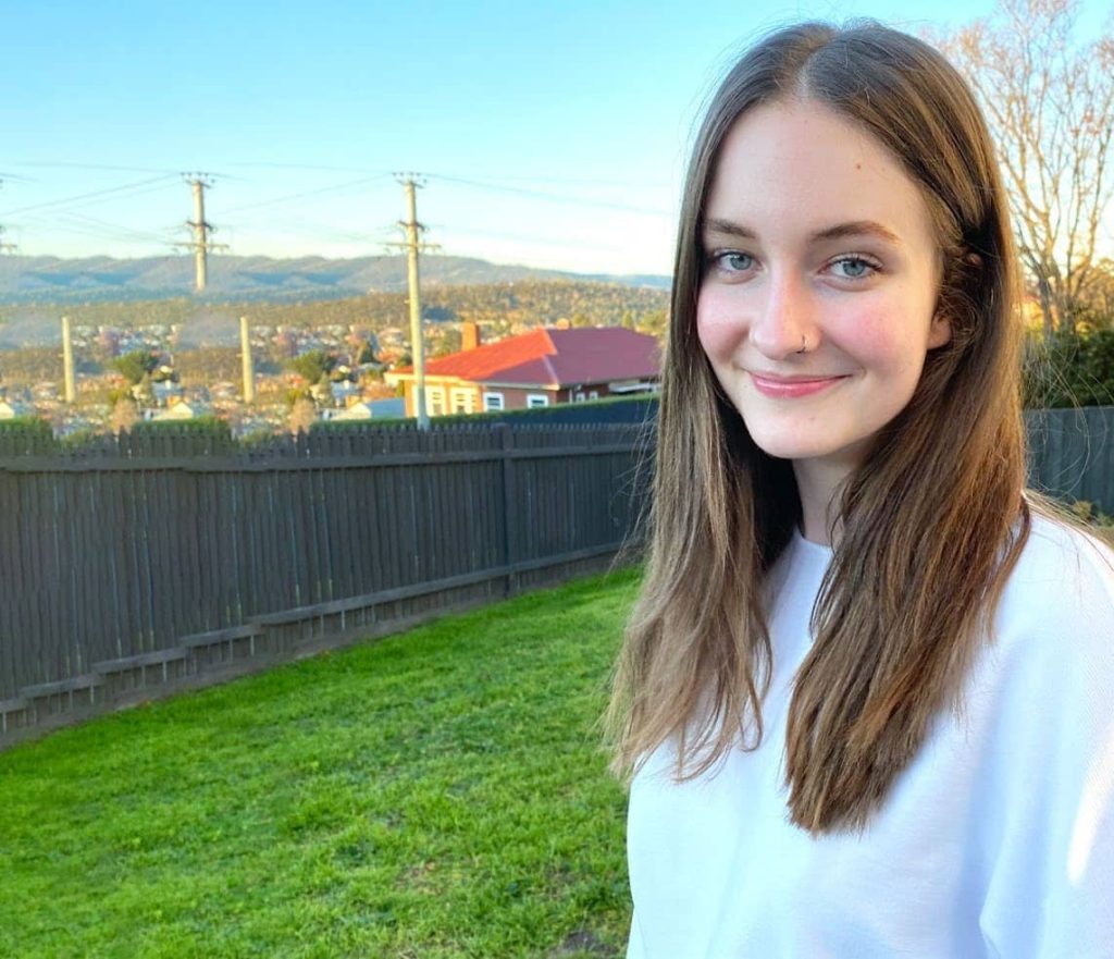 Photo of Lottie - a young woman standing in a grassy field.