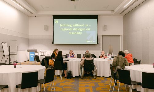 Photo of a group of women and non-binary people with disabilities sitting around a table on a conference room.